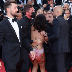 A nude woman is dragged away from the red carpet at Cannes Film Festival after staging a protest