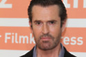 Rupert Everett tries to avoid his reflection as he ages