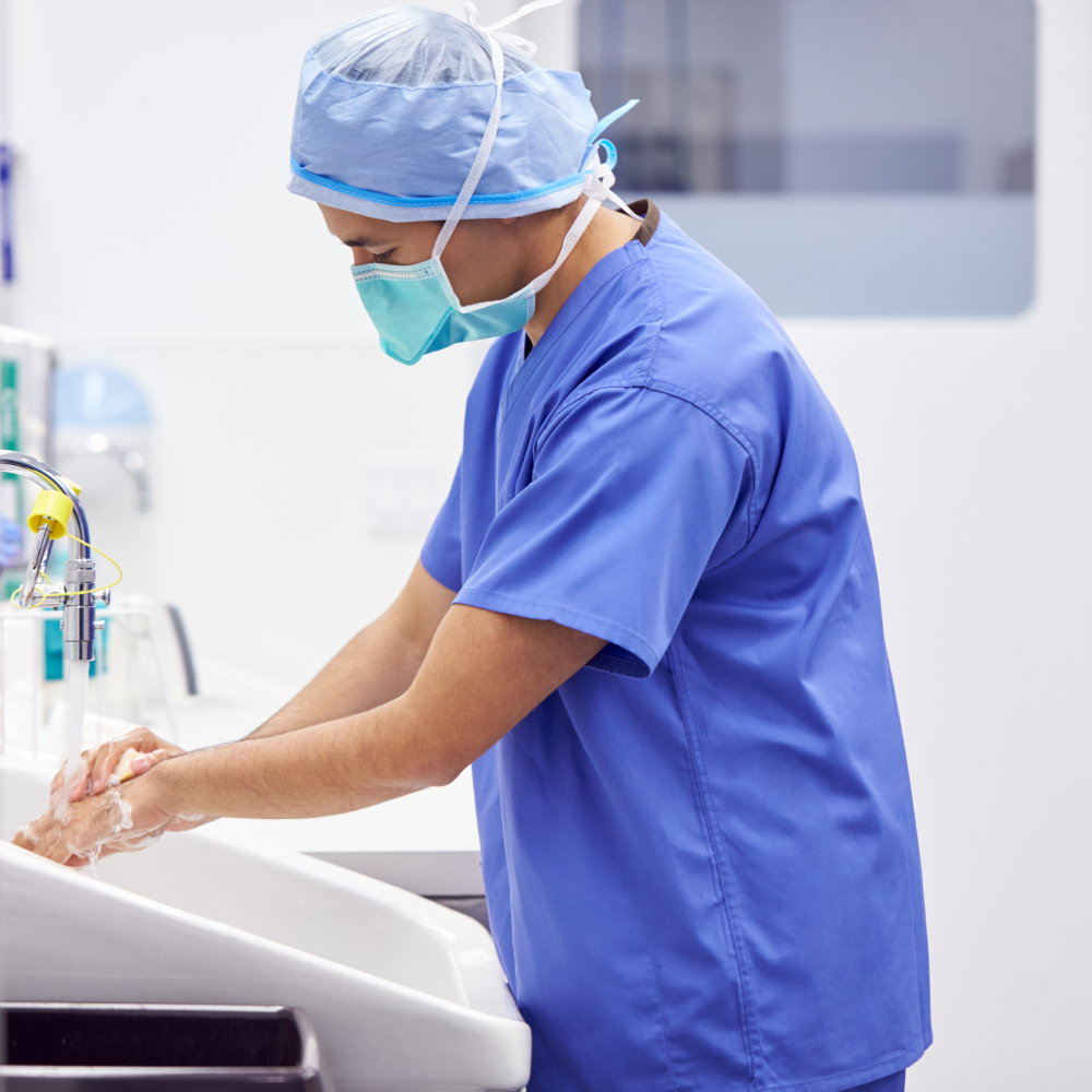 Male Surgeon Wearing Scrubs Washing Hands Before Operation In Hospital Operating Theater